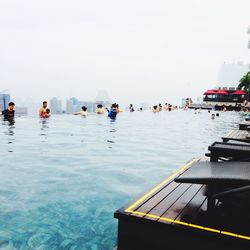 People enjoying in swimming pool at marina bay sands against clear sky