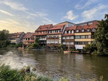 Buildings by river against sky