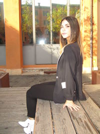 Side view of smiling young woman sitting outdoors