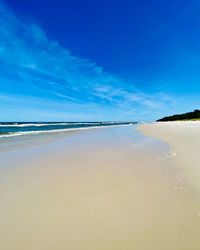 Scenic view of beach against blue sky