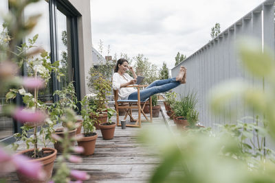 Smiling woman relaxing on balcony using tablet