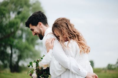 Close-up of couple embracing against sky