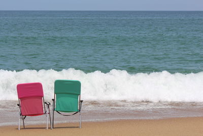 Red and green chairs on shore