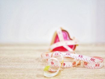 Close-up of tape measure by heart shape on table