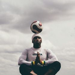 Low angle view of man holding camera against sky