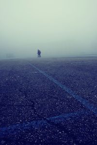 People walking on street against sky during foggy weather