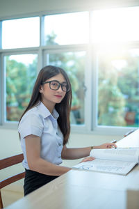 Young woman wearing eyeglasses on table