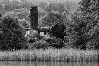 Built structure by trees on landscape against sky