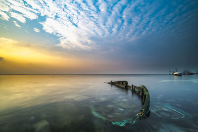 High angle view of shipwreck in sea against sky during sunset