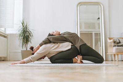 Attractive mother middle age woman and daughter teenager ptactice yoga together in the bright room