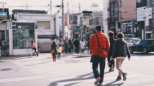 Rear view of people walking on city street