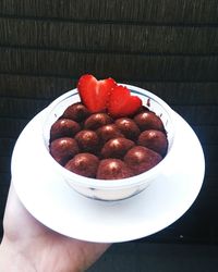 Close-up of hand holding strawberries in bowl