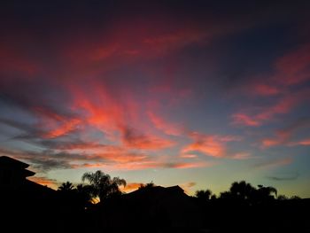 Low angle view of silhouette trees against dramatic sky