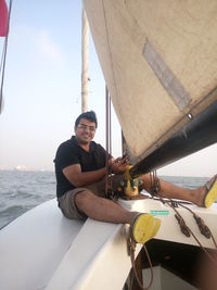 Portrait of smiling man sitting in sailboat on sea