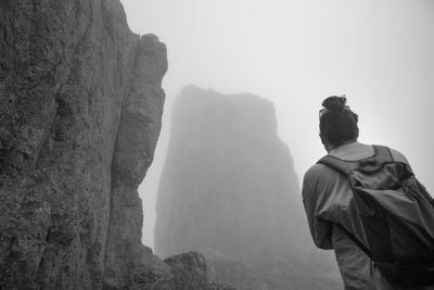 Rear view of women standing on rock against sky
