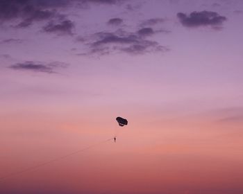 Low angle view of kite flying in sky at sunset