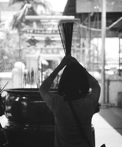 Rear view of woman with incense praying in temple