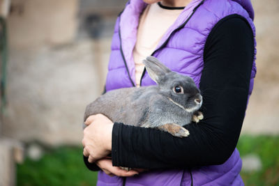Midsection of mid adult woman carrying cute rabbit while standing outdoors