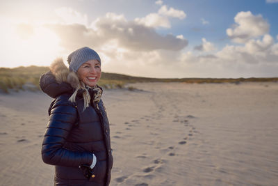 Portrait of smiling young woman standing on beach