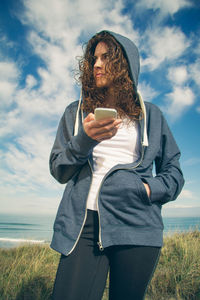 Full length of man holding camera while standing on field against sky