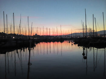 Sailboats moored in lake against sky during sunset