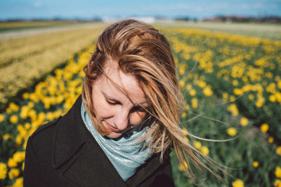 Portrait of woman with yellow narcissus flowers on field