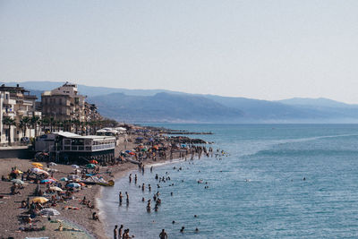 People on beach against clear sky