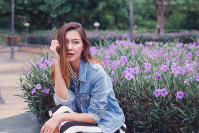 Beautiful young woman sitting on purple flowering plants