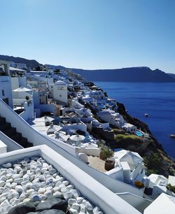 Buildings by sea against clear blue sky