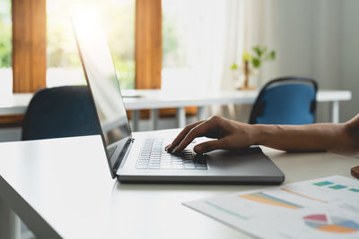 Midsection of businesswoman using laptop on table