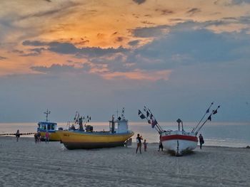 People on beach against sky during sunset