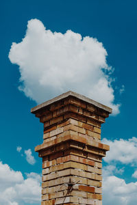 Low angle view of smoke stack against cloudy sky