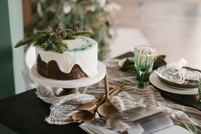 Chocolate cake with white icing, decorated with fir branches for christmas or new year on the served
