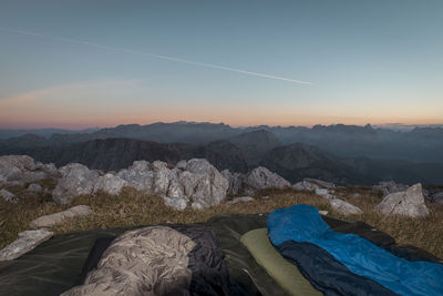 Beds at campsite on mountain peak against sky during sunset