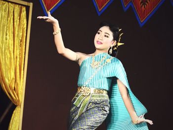 Portrait of young woman standing against wall