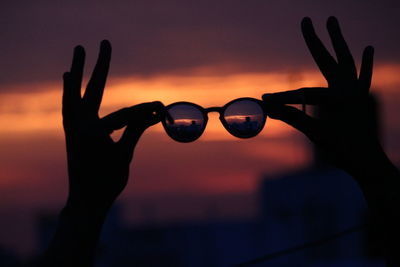 Close-up of silhouette hand against sky during sunset