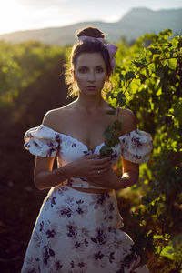 Brunette woman in a white dress stands in a vineyard in summer in italy