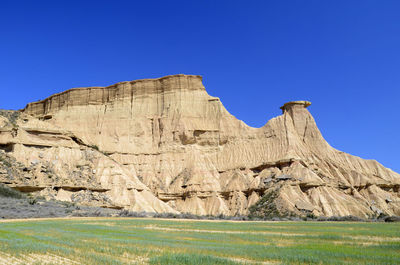 Rock formations on landscape against clear blue sky