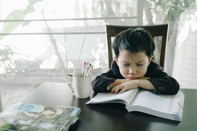 Portrait of boy with open book on table