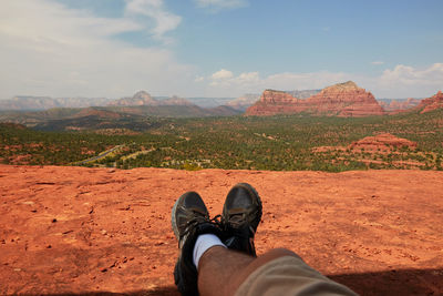 Low section of man standing on mountain against sky