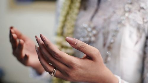 Midsection of woman gesturing while praying