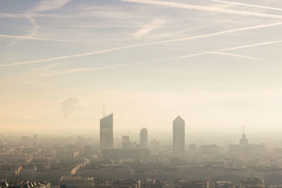 Aerial view of buildings in city with air pollution at sunset