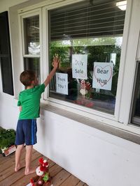 Rear view of boy standing by window