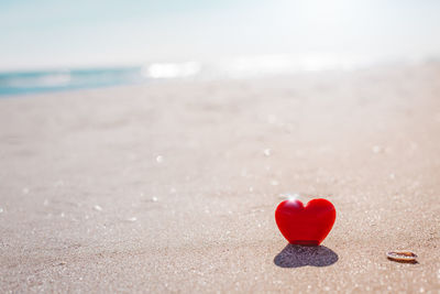 Heart shape on sand at beach against sky