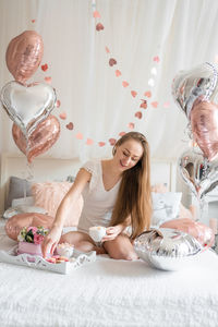 Portrait of smiling woman sitting on bed at home