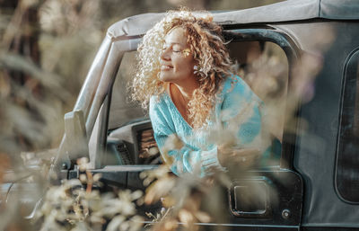 Portrait of young woman standing in car