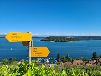 Information sign by sea against clear blue sky