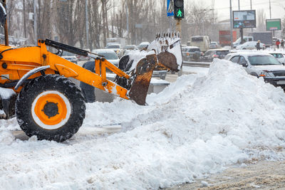 A fragment of powerful municipal equipment clearing snow on a city street in winter during snowfall.