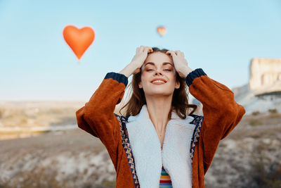 Portrait of young woman standing against sky