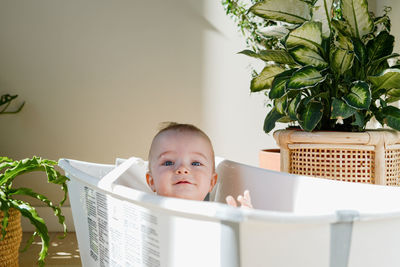 Portrait of cute baby boy sitting in bathtub at home